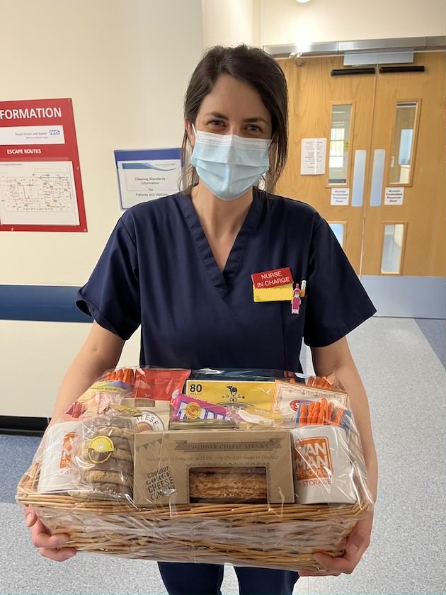 A nurse in uniform holding a hamper of food